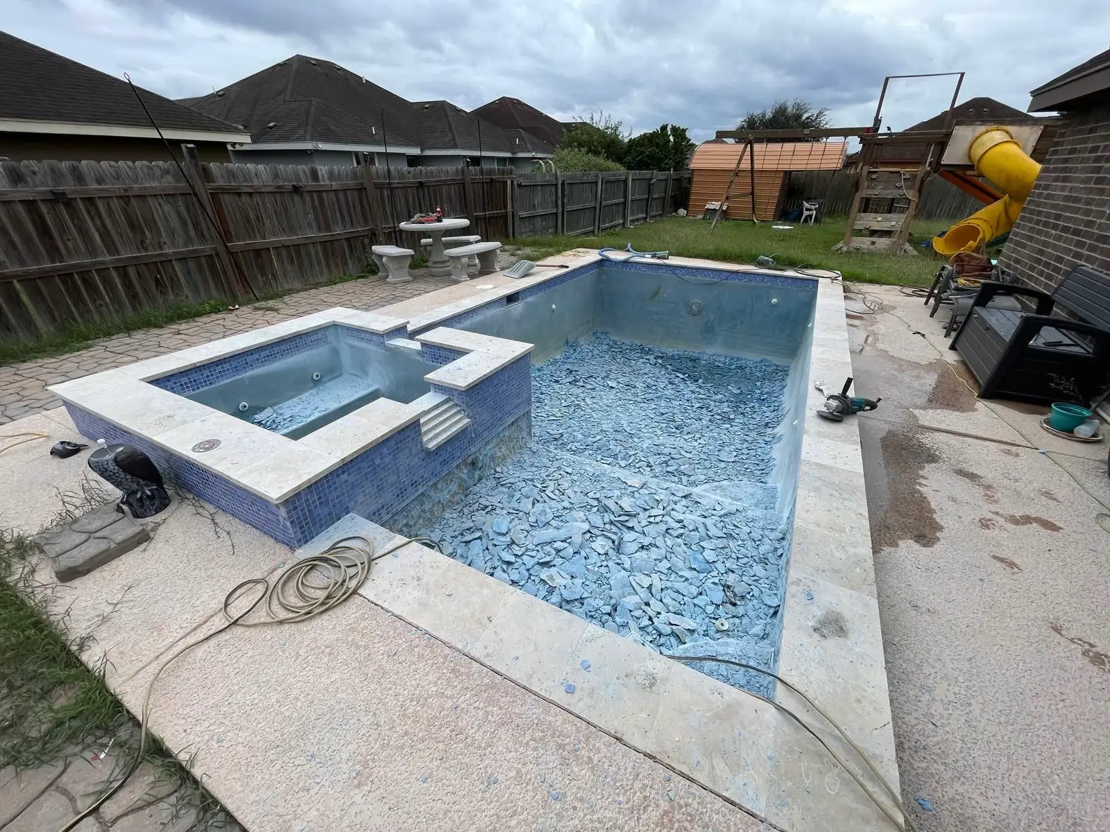 Pool and spa with old plaster chipped out, broken plaster pieces covering the floor